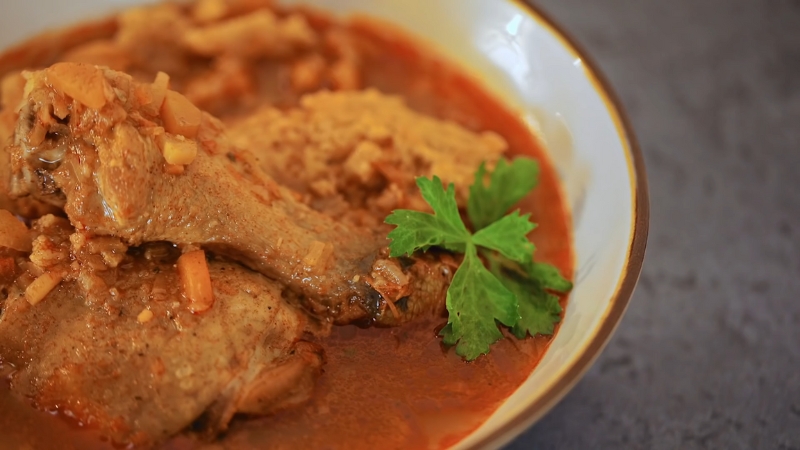 Pileći paprikaš sa knedlama u tanjiru na stolu