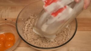 Osoba dodaje umućena belanca u smesu sa orasima i brašnom